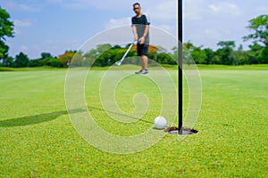 Golfer putt golf ball into hole on the green at golf course