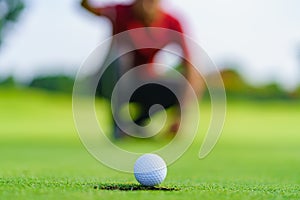 Golfer putt golf ball into hole on the green at golf course