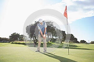 Golfer putting ball on the green