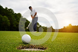 Golfer putting ball on the green golf, lens flare on sun set evening time