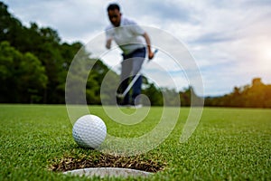 Golfer putting ball on the green golf, lens flare on sun set evening time