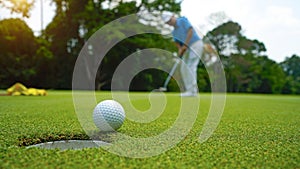 Golfer putting ball on the green golf, lens flare on sun set evening time