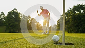 Golfer putting ball on the green golf, lens flare on sun set evening time