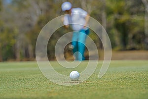 Golfer putting ball on the green golf, lens flare on sun set evening time. Golfer action to win after long putting golf ball in to