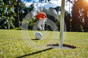 Golfer putting ball on the green golf, lens flare on sun set evening time. Golfer action to win after long putting golf ball in to