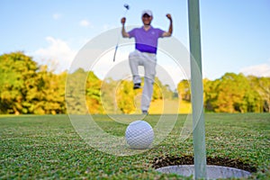 Golfer putting ball on the green golf, lens flare on sun set evening time. Golfer action to win after long putting golf ball in to