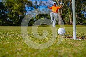 Golfer putting ball on the green golf, lens flare on sun set evening time. Golfer action to win after long putting golf ball in to