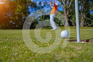 Golfer putting ball on the green golf, lens flare on sun set evening time. Golfer action to win after long putting golf ball in to