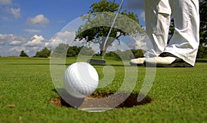 Golfer putting ball into hole