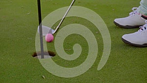 Golfer putting the ball into the hole