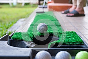 Golfer putting a golf ball into the edge hole