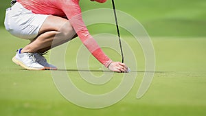 Golfer putting golf ball on green grass for check fairway to hole