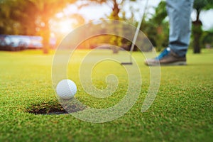 Golfer putting golf ball on the green golf, lens flare on sun set evening time, Pro Golf long putting golf ball in to the hole, su