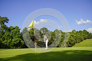 Golfer putting golf in a beautiful golf course in the evening with a sunset background in Thailand