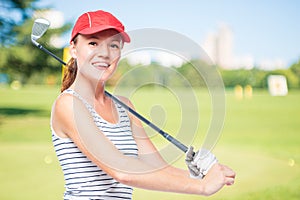 Golfer putting golf stick on shoulder while smiling