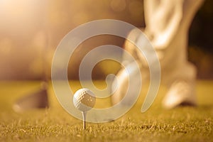 Golfer standing behind teed golf ball low angle with sun flare