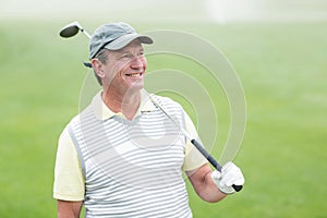 Golfer standing and swinging his club smiling at camera
