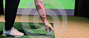 Golfer in studio put golf ball on tee to play on simulator