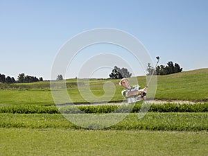 Golfer Swinging In Sand Trap