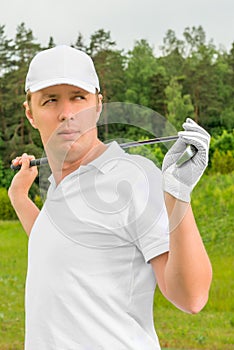 Golfer in a T-shirt and a baseball cap with golf club