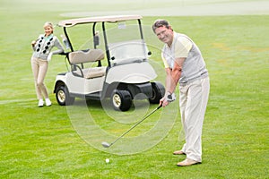 Golfer about to tee off with partner behind him