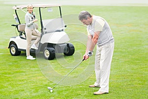 Golfer about to tee off with partner behind him