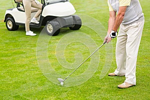 Golfer about to tee off with partner behind him