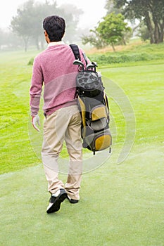 Golfer walking away holding golf bag