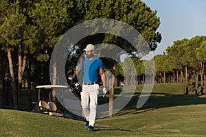 Golfer walking and carrying golf bag
