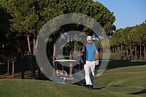 Golfer walking and carrying golf bag