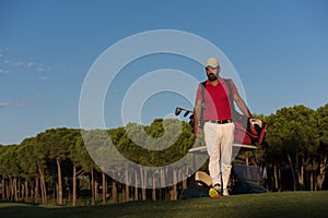 Golfer walking and carrying golf bag