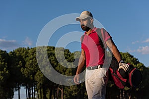 Golfer walking and carrying golf bag