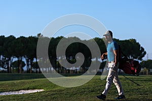 Golfer walking and carrying golf bag at beautiful sunset