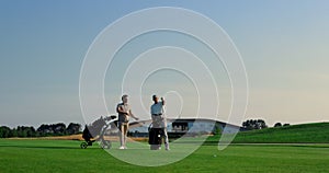 Golfers discuss course game competition outside. Two men choose putters on field