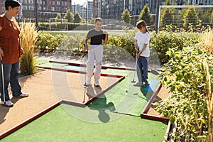 golfers with parents playing golf at sunny day