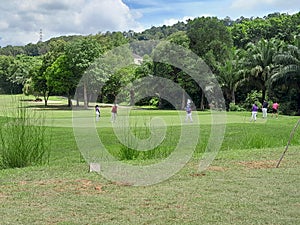golfers are playing on the batam city golf course with green grass that looks so beautiful and amazing.
