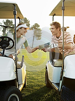 Golfers Sitting In Golf Carts Holding Score Card