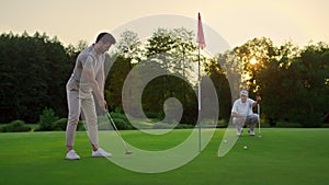 Golfers team hitting ball on sunset field course. Two players missing golf shot.