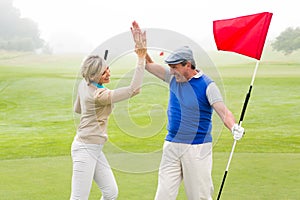 Golfing couple high fiving on the golf course