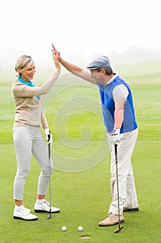 Golfing couple high fiving on the golf course