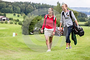 Golfing couple walking together on golf course photo