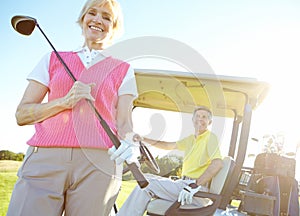 Golfing is her favorite pastime. Low angle shot of an attractive older female golfer standing in front of a golf cart