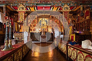 Gompa of one of the Buddhist monasteries with gilded Buddha on the altar, and ritual musical instruments on foreground