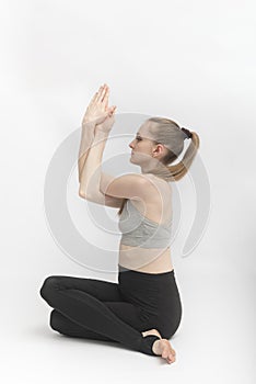 Gomukhasana. Cow Face Pose. Slender and flexible young woman practices yoga. Hatha yoga. Side view