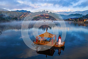 Gondola boat in the middle of a mist-covered lake at Ban Rak Thai, Mae Hong Son Province, Thailand