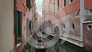 Gondola go down canal at day, Venice, Italy. Gondolier navigate boat. Tourists enjoy ride and take photos. Medieval