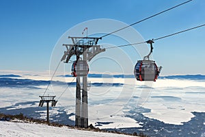 Gondola lift. Cabin of ski-lift in the ski resort in the early morning at dawn with mountain peak in the distance