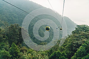 Gondola lifts moving over mountain with green trees in the area of Sun Moon Lake Ropeway in Yuchi Township, Nantou County, Taiwan