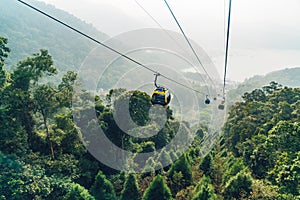 Gondola lifts moving over mountain with green trees in the area of Sun Moon Lake Ropeway in Yuchi Township, Nantou County, Taiwan