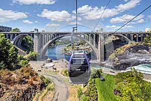 Gondolas fly over the Spokane River and falls near Riverfront Park on a summer day in Spokane, Washington, USA